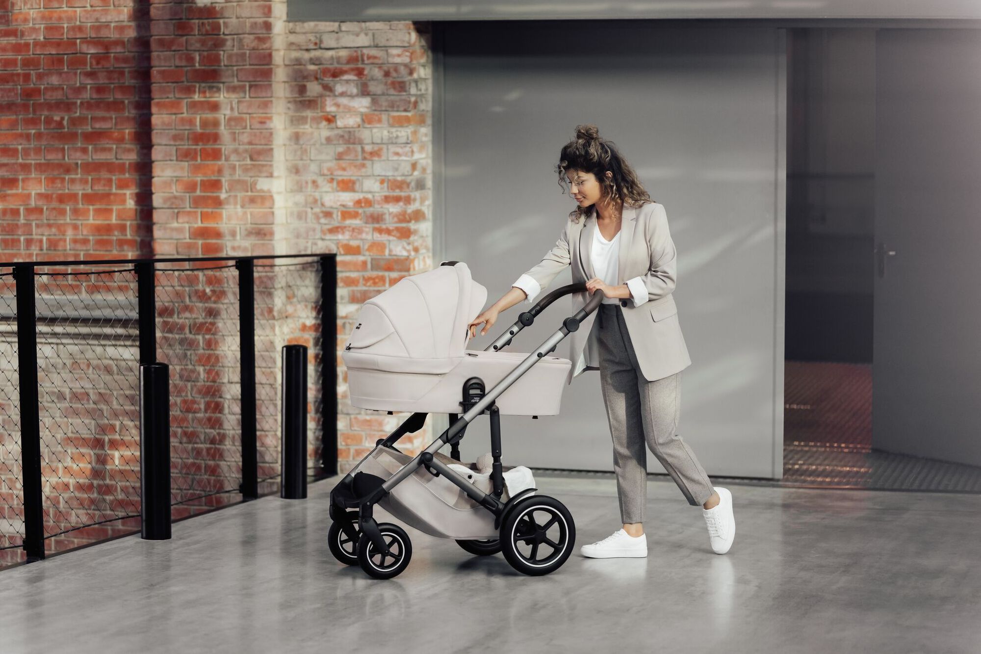 Genitore che spinge un passeggino SMILE 5Z con navicella, controllando delicatamente il bambino.